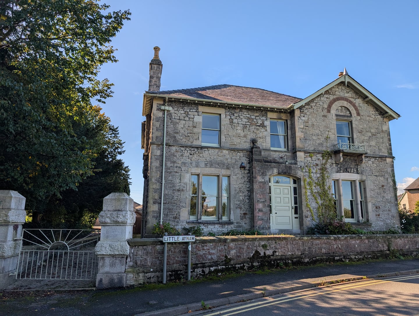 The stone front of Olrig Bank beneath a blue sky, viewed from Little Aynam